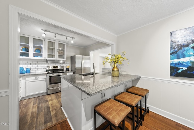 7 Meadowbrook Ave, Durham, NC 27712 - kitchen featuring appliances with stainless steel finishes, stone countertops, glass insert cabinets, dark wood-style floors, and a peninsula