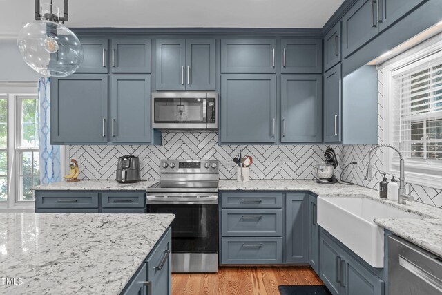 511 Scotts Ridge Trl, Apex, NC 27502 - kitchen featuring stainless steel appliances, backsplash, light wood-style flooring, light stone counters, and hanging light fixtures