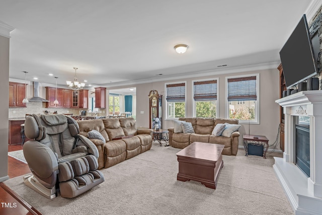 1950 Firenza Dr, Apex, NC 27502 - living room with a glass covered fireplace, crown molding, light carpet, a chandelier, and recessed lighting