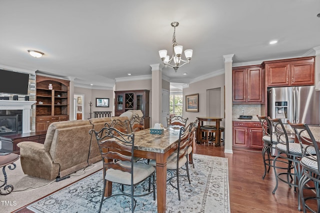 1950 Firenza Dr, Apex, NC 27502 - dining room with crown molding, recessed lighting, dark wood finished floors, a chandelier, and ornate columns