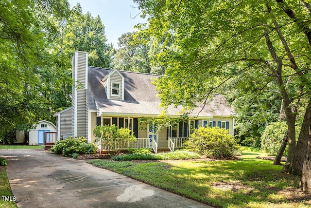 3104 Braywood Ct, Apex, NC 27539 - new england style home featuring covered porch, a shed, a chimney, a front lawn, and roof with shingles