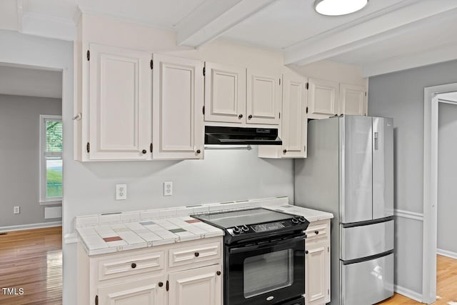 3104 Braywood Ct, Apex, NC 27539 - kitchen with black range with electric cooktop, under cabinet range hood, beamed ceiling, white cabinetry, and freestanding refrigerator