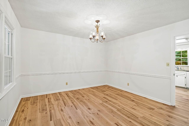 2330 Thunder Rd, Durham, NC 27712 - unfurnished room with light wood finished floors, a chandelier, and a textured ceiling