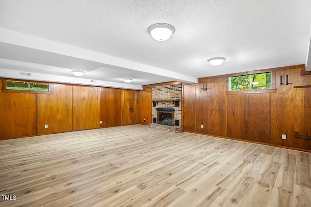 2330 Thunder Rd, Durham, NC 27712 - unfurnished living room with a textured ceiling, light wood-style flooring, wood walls, and a brick fireplace