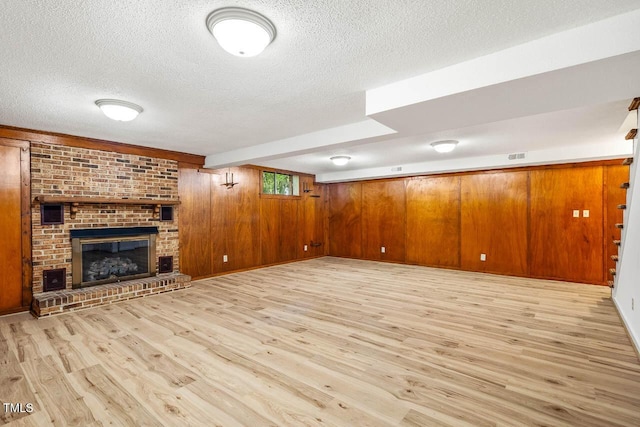 2330 Thunder Rd, Durham, NC 27712 - unfurnished living room with a textured ceiling, light wood-type flooring, wooden walls, and a brick fireplace