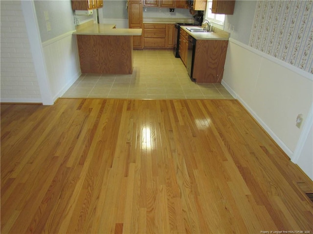 310 N Farmers Rd, Fayetteville, NC 28311 - kitchen with light countertops, brown cabinetry, a peninsula, light wood finished floors, and dishwasher