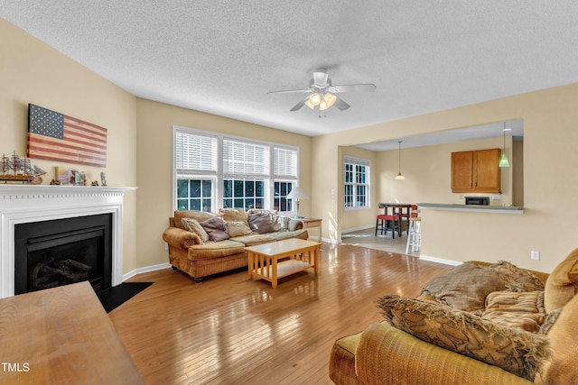 2114 Baycourt Trl, Hillsborough, NC 27278 - living room with a ceiling fan, light wood-type flooring, a fireplace with flush hearth, and a textured ceiling