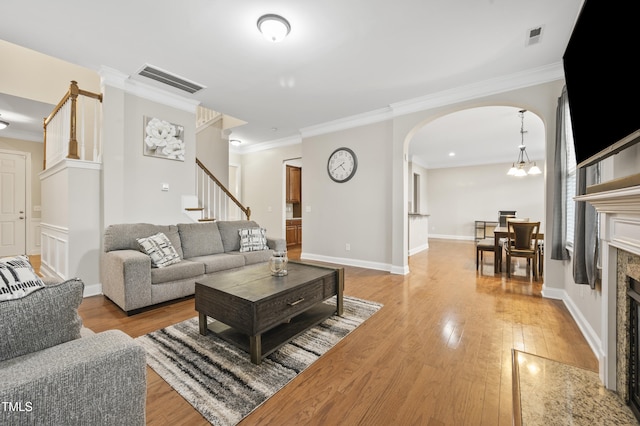 1204 Chapanoke Rd, Raleigh, NC 27603 - living area featuring light wood-style flooring, arched walkways, ornamental molding, stairs, and a tile fireplace