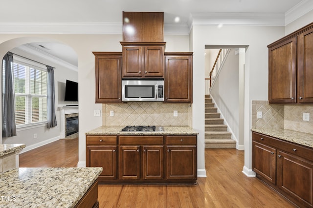1204 Chapanoke Rd, Raleigh, NC 27603 - kitchen with appliances with stainless steel finishes, light wood-style floors, arched walkways, light stone counters, and ornamental molding