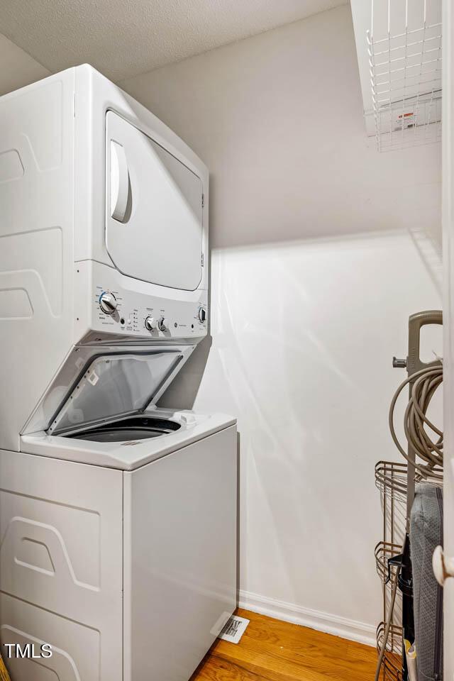 7 Georgetown Ct, Durham, NC 27705 - washroom featuring stacked washer / dryer and wood finished floors