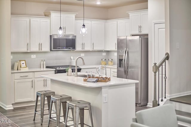 1004 Citadel Ave, Durham, NC 27713 - kitchen featuring appliances with stainless steel finishes, white cabinets, dark wood-style floors, light countertops, and an island with sink