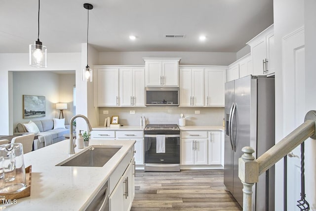 1004 Citadel Ave, Durham, NC 27713 - kitchen featuring appliances with stainless steel finishes, light wood-style flooring, white cabinetry, pendant lighting, and decorative backsplash