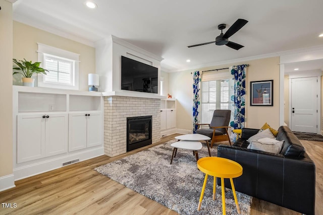 309 N Mason St, Apex, NC 27502 - living room featuring ceiling fan, ornamental molding, plenty of natural light, wood finished floors, and a brick fireplace