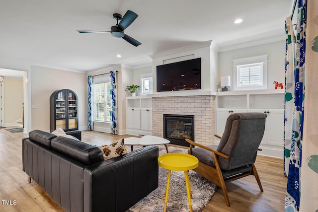 309 N Mason St, Apex, NC 27502 - living area featuring ornamental molding, a brick fireplace, light wood-style floors, a ceiling fan, and plenty of natural light