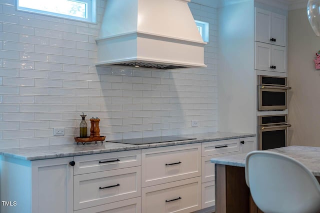 309 N Mason St, Apex, NC 27502 - kitchen featuring custom range hood, backsplash, black electric stovetop, white cabinets, and stainless steel double oven