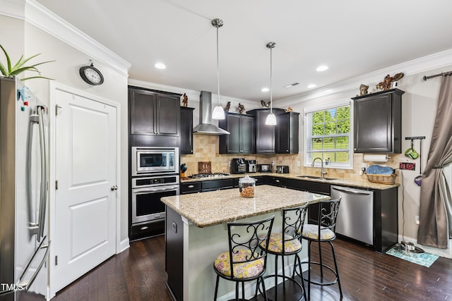 90 E Calvert Ct, Clayton, NC 27527 - kitchen featuring appliances with stainless steel finishes, wall chimney exhaust hood, crown molding, dark wood-style floors, and a kitchen island