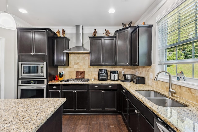 90 E Calvert Ct, Clayton, NC 27527 - kitchen featuring appliances with stainless steel finishes, wall chimney range hood, dark wood-type flooring, ornamental molding, and light stone counters