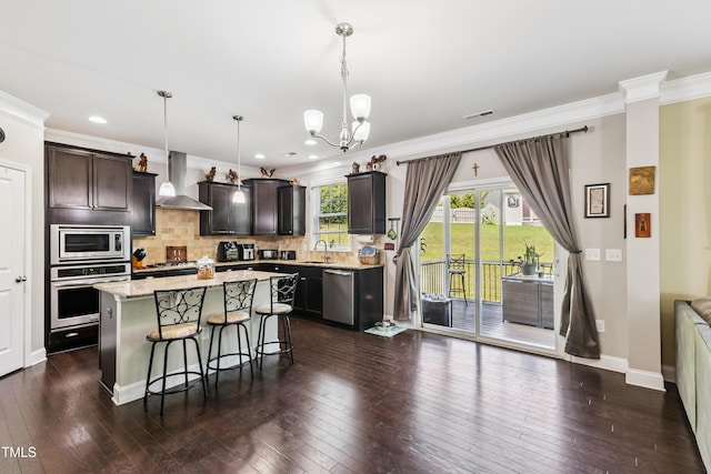 90 E Calvert Ct, Clayton, NC 27527 - kitchen featuring stainless steel appliances, wall chimney range hood, a chandelier, a kitchen bar, and dark wood-style floors
