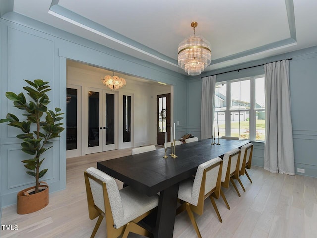 3666 Jordan Estates Way, New Hill, NC 27562 - dining space featuring a chandelier, a decorative wall, a tray ceiling, and light wood-type flooring