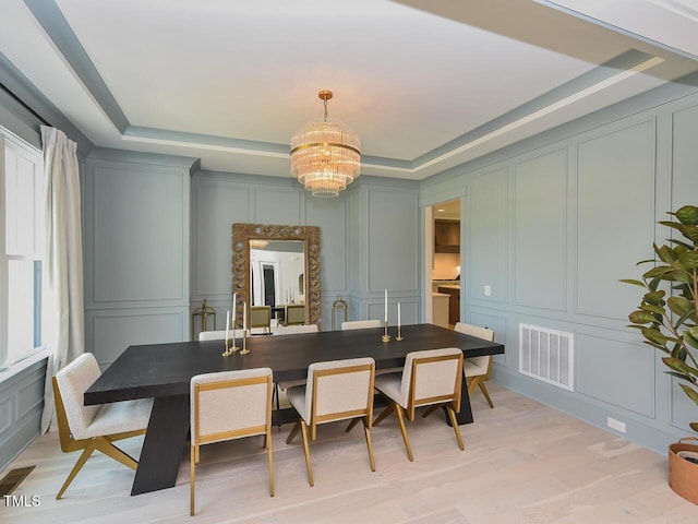 3666 Jordan Estates Way, New Hill, NC 27562 - dining area featuring a decorative wall, a chandelier, light wood-type flooring, and a raised ceiling