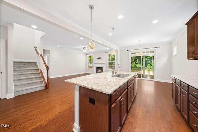 316 Rapport Dr, Cary, NC 27519 - kitchen with a warm lit fireplace, a kitchen island with sink, pendant lighting, dark wood-style floors, and recessed lighting