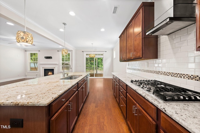 316 Rapport Dr, Cary, NC 27519 - kitchen featuring stainless steel appliances, wall chimney range hood, dark wood finished floors, tasteful backsplash, and a warm lit fireplace
