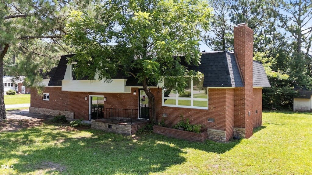 1617 Chase St, Rocky Mount, NC 27801 - view of front of property with a front yard, brick siding, a chimney, and roof with shingles