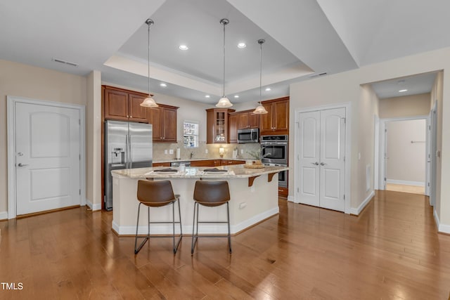 936 Blue Bird Ln, Wake Forest, NC 27587 - kitchen featuring appliances with stainless steel finishes, a raised ceiling, brown cabinets, tasteful backsplash, and recessed lighting