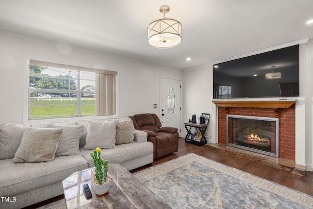 1319 Legend Rd, Raleigh, NC 27603 - living room featuring wood finished floors, ornamental molding, a brick fireplace, and recessed lighting