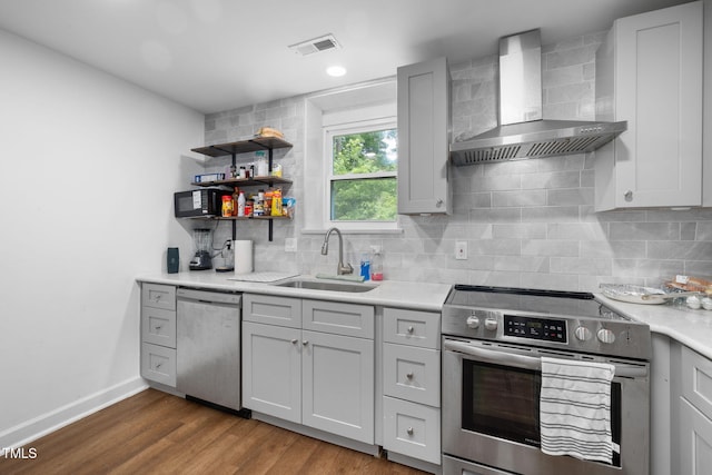 1319 Legend Rd, Raleigh, NC 27603 - kitchen featuring wall chimney exhaust hood, stainless steel appliances, light countertops, decorative backsplash, and dark wood-type flooring
