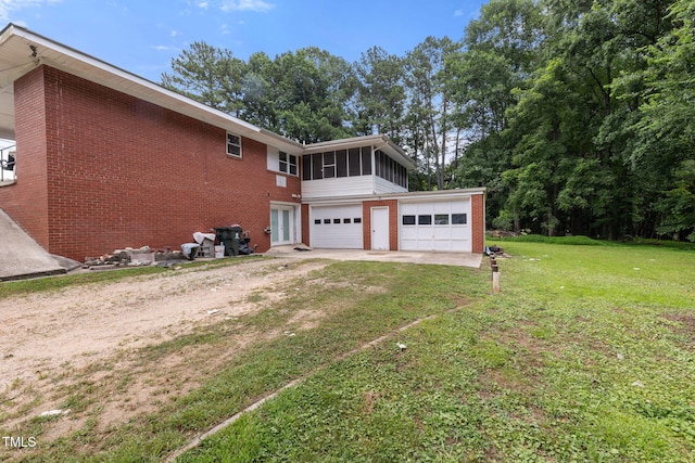 1319 Legend Rd, Raleigh, NC 27603 - view of property exterior featuring a sunroom, dirt driveway, brick siding, a lawn, and a garage