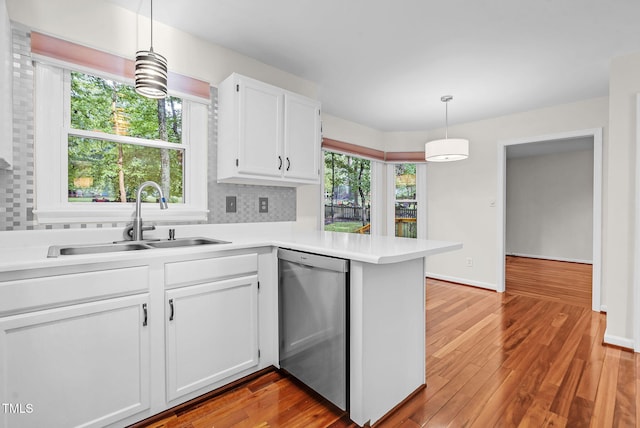 7 Nadeau Ct, Durham, NC 27704 - kitchen featuring stainless steel dishwasher, wood finished floors, light countertops, white cabinets, and plenty of natural light