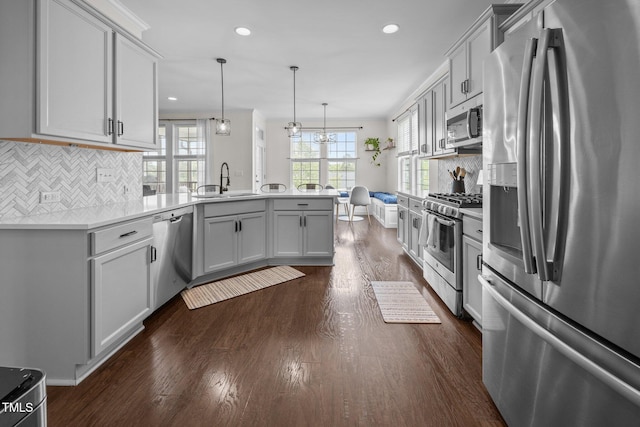 1304 Bromby Ave, Knightdale, NC 27545 - kitchen with appliances with stainless steel finishes, a peninsula, dark wood-type flooring, backsplash, and recessed lighting