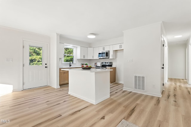 104 S Nikol Way, Clayton, NC 27520 - kitchen with appliances with stainless steel finishes, light wood-style flooring, light countertops, a center island, and crown molding