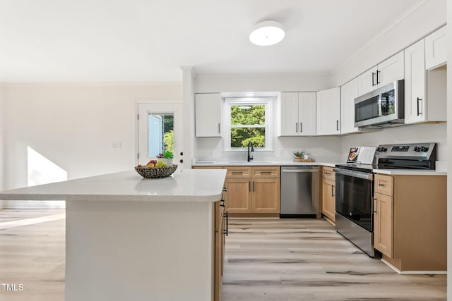 104 S Nikol Way, Clayton, NC 27520 - kitchen featuring appliances with stainless steel finishes, ornamental molding, light wood finished floors, a kitchen island, and light stone countertops