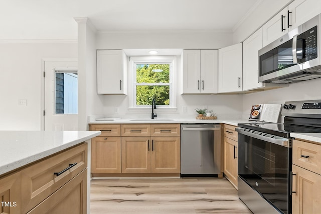 104 S Nikol Way, Clayton, NC 27520 - kitchen featuring appliances with stainless steel finishes, ornamental molding, light wood-type flooring, white cabinetry, and light stone countertops