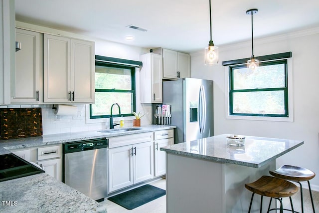 1523 Ivy Ln, Raleigh, NC 27609 - kitchen featuring appliances with stainless steel finishes, backsplash, light stone countertops, a breakfast bar area, and a kitchen island