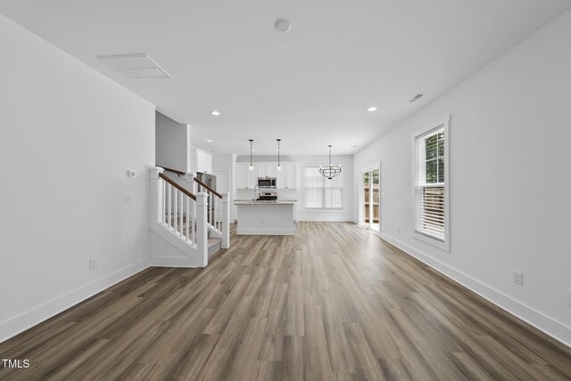 1254 Camden Ave, Durham, NC 27701 - unfurnished living room featuring dark wood-type flooring, stairs, recessed lighting, and a chandelier