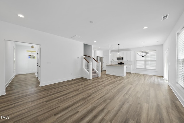 1254 Camden Ave, Durham, NC 27701 - unfurnished living room with wood finished floors, a chandelier, stairway, and recessed lighting