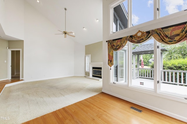 2944 Ballybunion Way, Raleigh, NC 27613 - unfurnished living room featuring healthy amount of natural light, a glass covered fireplace, high vaulted ceiling, light wood-style floors, and a ceiling fan