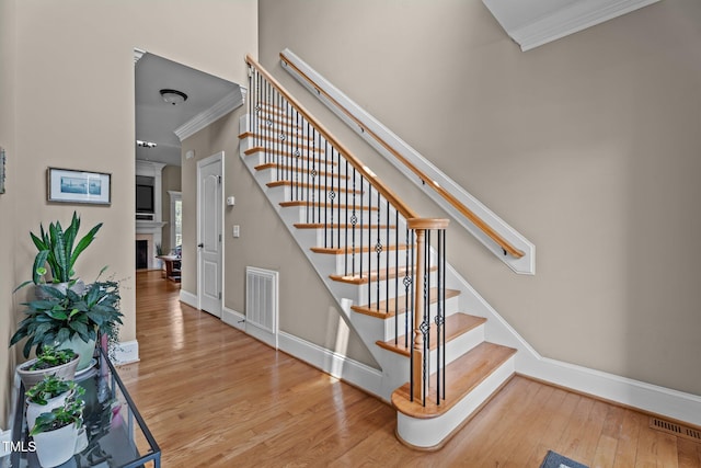 1012 Tavernier Knoll Ln, Raleigh, NC 27603 - stairway with crown molding, wood finished floors, and a fireplace