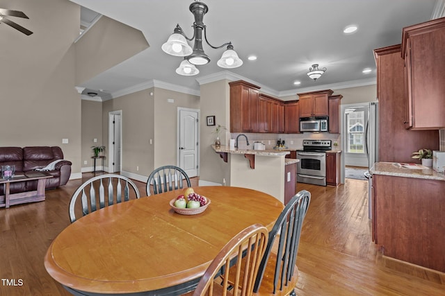 1012 Tavernier Knoll Ln, Raleigh, NC 27603 - dining space with wood finished floors, crown molding, recessed lighting, a ceiling fan, and a chandelier