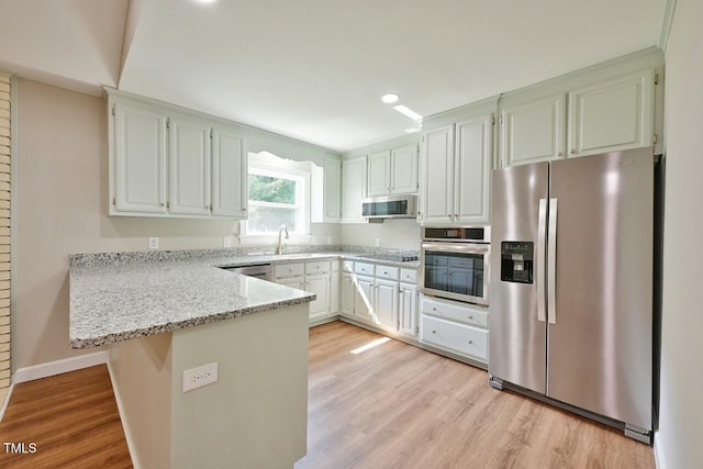 369 Historic Village Dr, Roxboro, NC 27574 - kitchen with stainless steel appliances, a peninsula, light wood-style floors, light stone counters, and recessed lighting