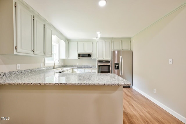 369 Historic Village Dr, Roxboro, NC 27574 - kitchen featuring appliances with stainless steel finishes, a peninsula, light wood-type flooring, light stone counters, and recessed lighting