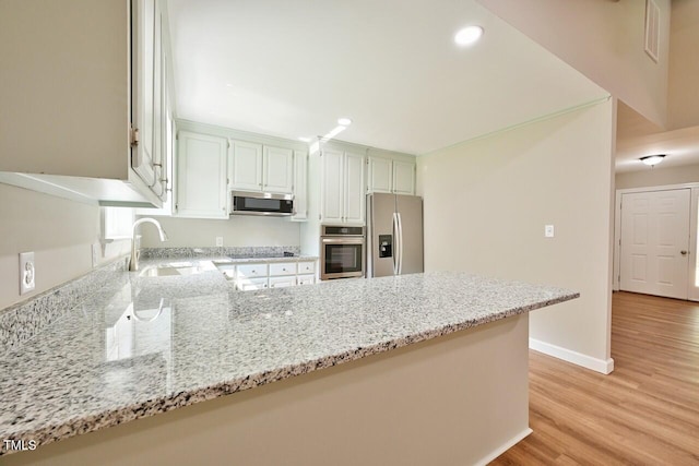 369 Historic Village Dr, Roxboro, NC 27574 - kitchen featuring stainless steel appliances, a peninsula, light wood-style floors, light stone counters, and recessed lighting