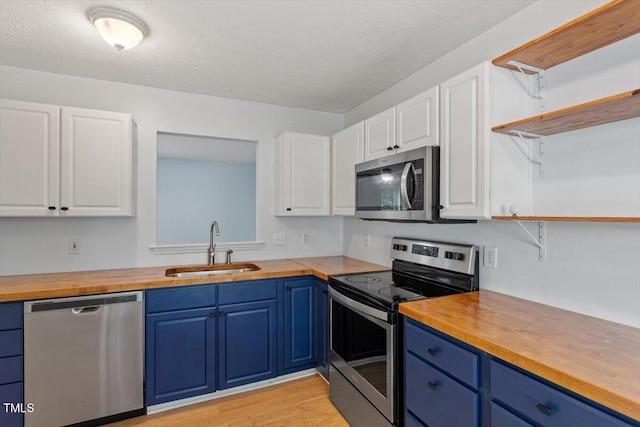 2733 Midway Park Ct, Raleigh, NC 27610 - kitchen featuring appliances with stainless steel finishes, wooden counters, open shelves, blue cabinetry, and a textured ceiling
