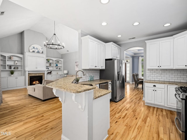 20 Little River Ct, Youngsville, NC 27596 - kitchen featuring appliances with stainless steel finishes, a peninsula, arched walkways, white cabinetry, and light wood-type flooring