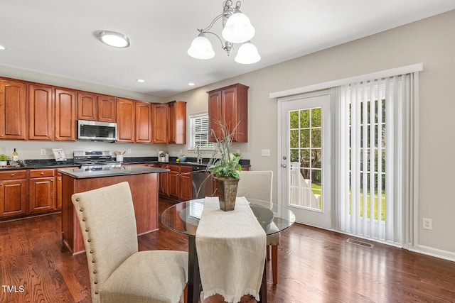 1201 Woodlands Creek Way, Apex, NC 27502 - kitchen with appliances with stainless steel finishes, a chandelier, a center island, brown cabinets, and dark countertops