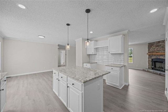 1271 Nutgrass Rd, Bunnlevel, NC 28323 - kitchen with open floor plan, light wood-style flooring, a textured ceiling, hanging light fixtures, and white cabinetry