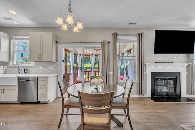 2714 Magnolia Tree Ln, Durham, NC 27703 - dining area with a chandelier, light wood-style flooring, a fireplace with flush hearth, and recessed lighting